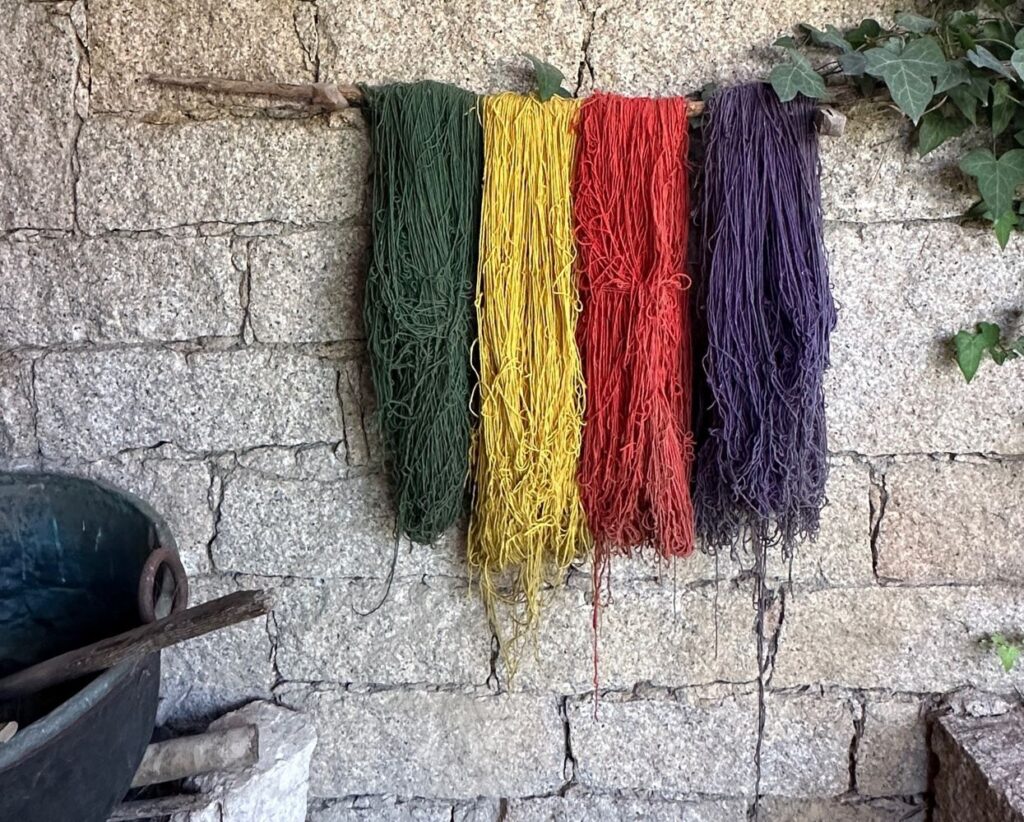 block wall with colourful yarns hanging on it